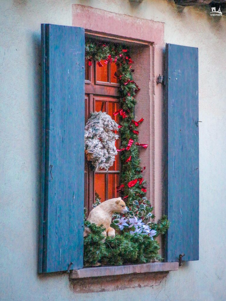 Decoración navideña en una ventana de Riquewihr